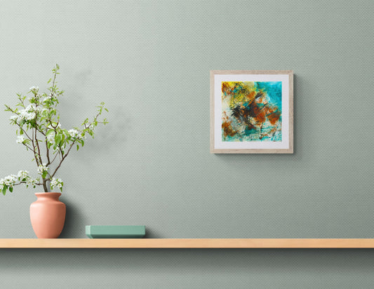 Framed abstract painting on a wall above a wooden shelf with a vase and plant.