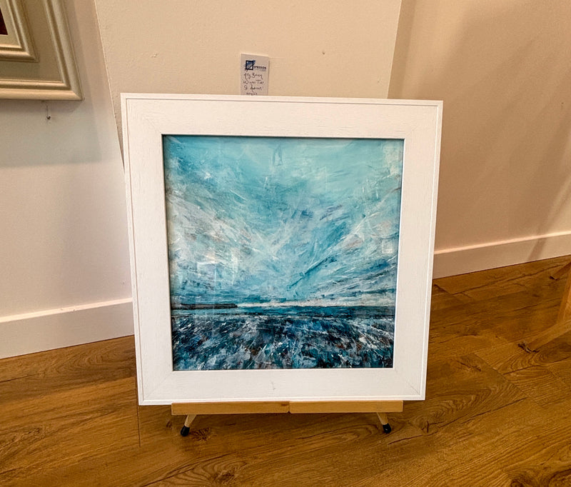 Framed abstract painting on an easel against a beige wall.