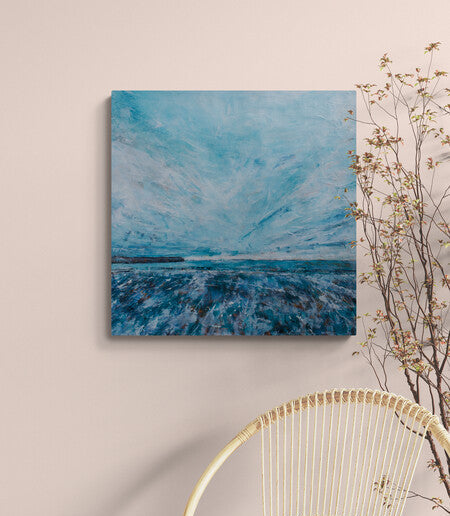 Abstract blue painting on a beige wall with a decorative chair and plant.